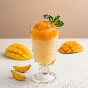 Firefly Un granité à base de glace pilée et de jus de mangue dans un verre haut. Le granité est bico.webp